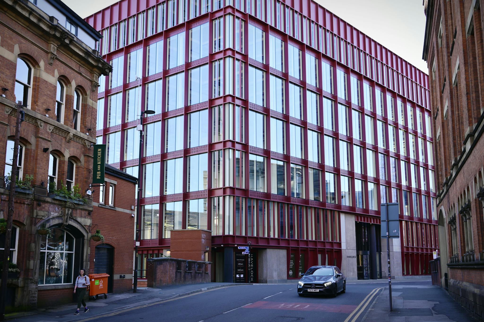 Contemporary red and glass building on a quiet city street with historical architecture.