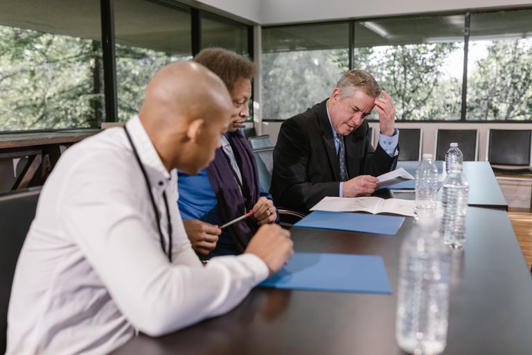 The MAR Legal Blog 8 Group of diverse colleagues in a business meeting reviewing documents indoors.